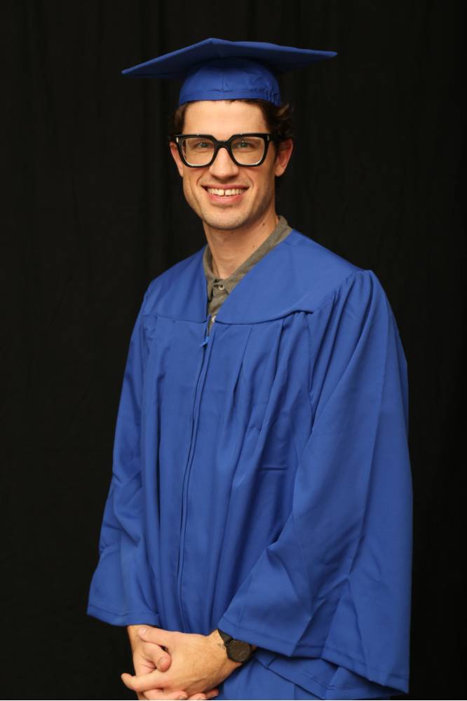 student in cap and gown takes a picture